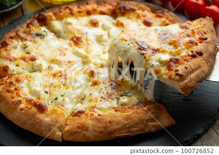 A slice of hot Italian pizza with stretching cheese. Pizza four cheeses with basil. A slice of hot Italian pizza with stretching cheese. Pizza four cheeses with basil. 100726852