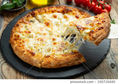 A slice of hot Italian pizza with stretching cheese. Pizza four cheeses with basil. 100726880