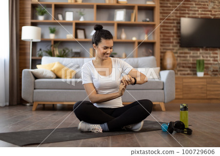 Lady monitoring workout achievements on smartwatch at home Lady monitoring workout achievements on smartwatch at home 100729606
