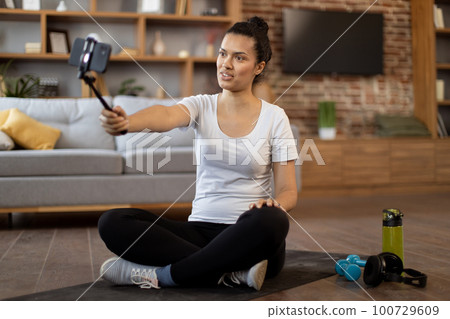 Young coach live streaming fitness tutorial via cell phone Young coach live streaming fitness tutorial via cell phone 100729609
