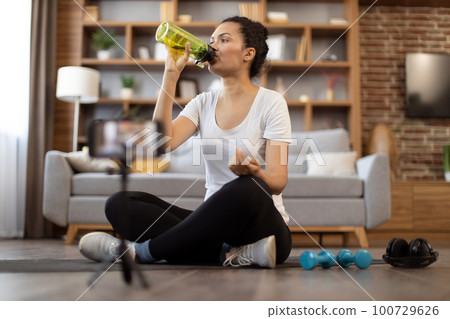 Fit sports vlogger showing online workout routine at home Fit sports vlogger showing online workout routine at home 100729626