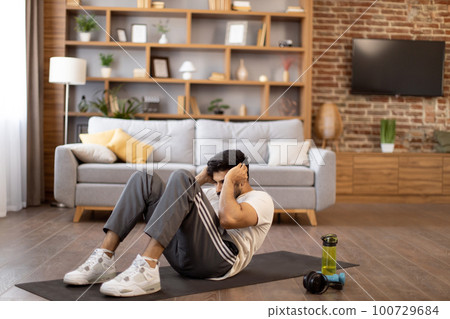 Active indian man training abs with body crunches 100729684