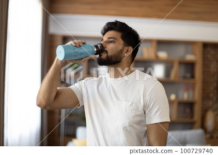 Arabian man drinking water after domestic workout 100729740