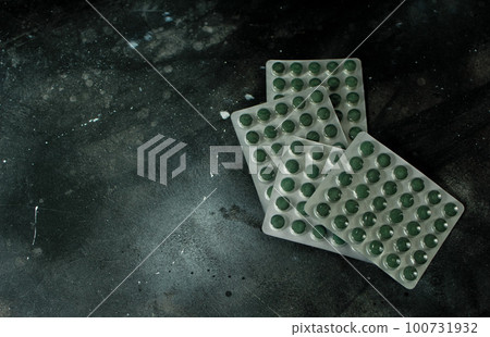 Chlorella or spirulina tablets on dark background Chlorella or spirulina tablets on dark background 100731932