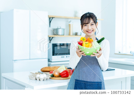 Young woman with salad bowl in the kitchen 100733142