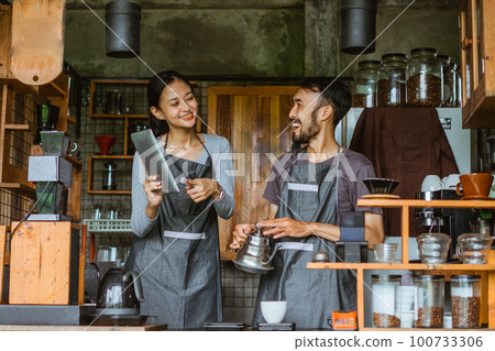 female barista smiling while pointing at the digital tablet 100733306