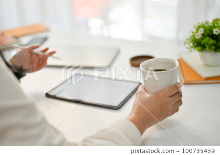 Cropped image of a female freelancer remote working at the coffee shop, sipping coffee Cropped image of a female freelancer remote working at the coffee shop, sipping coffee 100735439