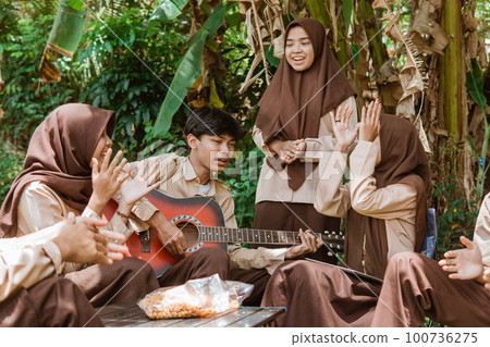 Boy Scouts and Girl Scouts sing together using a guitar Boy Scouts and Girl Scouts sing together using a guitar 100736275