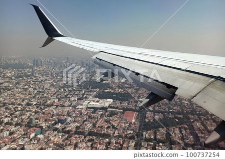 View on Mexico city through airplane window of commercial jet plane landing in local airport. Air travelling concept View on Mexico city through airplane window of commercial jet plane landing in local airport. Air travelling concept 100737254