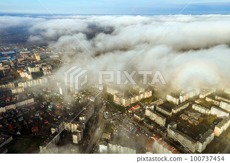 Top aerial view of fluffy white clouds over modern city with high rise buildings. Top aerial view of fluffy white clouds over modern city with high rise buildings. 100737454