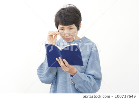 Middle-aged woman reading with reading glasses on a white background Middle-aged woman reading with reading glasses on a white background 100737649