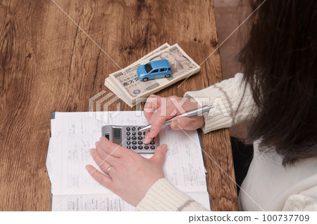 [Housewife doing calculations for buying a car] 100737709