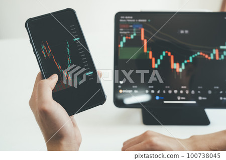 Hand shot of person trading online with phone and tablet. 100738045