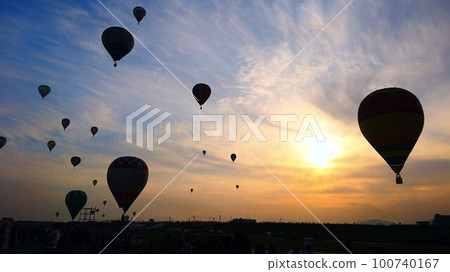 Silhouette of a hot air balloon flying in the orange blue evening sky Silhouette of a hot air balloon flying in the orange blue evening sky 100740167