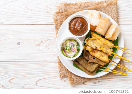 Pork Satay with your Peanut Sauce  and pickles which are cucumber slices and onions in vinegar 100741261