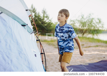 cute little caucasian boy helping to put up a tent. Family camping concept cute little caucasian boy helping to put up a tent. Family camping concept 100744430