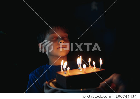 little cute caucasian boy making a wish before puffing out a candle on cake on his 6 birthday little cute caucasian boy making a wish before puffing out a candle on cake on his 6 birthday 100744434