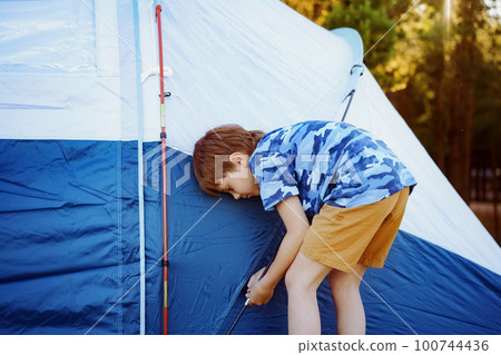 cute little caucasian boy helping to put up a tent. Family camping concept 100744436