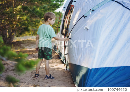 cute little caucasian boy helping to put up a tent. Family camping concept 100744650