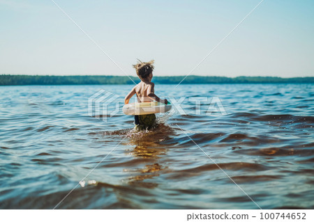 cute caucasian boy running into water with splashes and laughter. Vacation on sea side. Happy childhood. Image with selective focus cute caucasian boy running into water with splashes and laughter. Vacation on sea side. Happy childhood. Image with selective focus 100744652