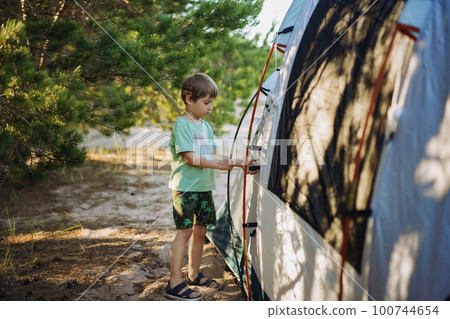 cute little caucasian boy helping to put up a tent. Family camping concept cute little caucasian boy helping to put up a tent. Family camping concept 100744654