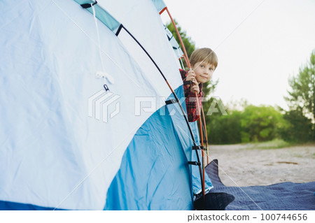 cute little caucasian boy looking out from touristic tent. Family camping concept 100744656