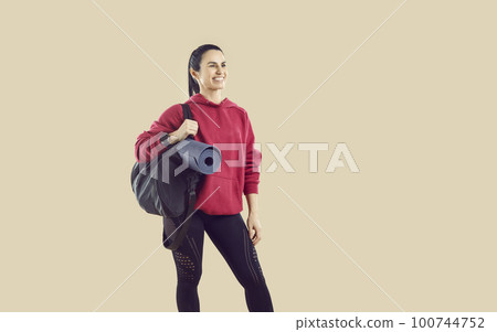 Happy fit woman with sports bag standing isolated on beige copy space background 100744752