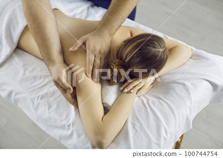 Relaxed young female client enjoys therapeutic body massage in spa or wellness center. Relaxed young female client enjoys therapeutic body massage in spa or wellness center. 100744754