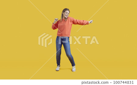 Happy young woman dancing on yellow background 100744831
