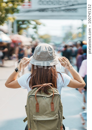 woman traveler visiting in Bangkok, Tourist with backpack and hat sightseeing in Chatuchak Weekend Market, landmark and popular attractions in Bangkok, Thailand. Travel in Southeast Asia concept woman traveler visiting in Bangkok, Tourist with backpack and hat sightseeing in Chatuchak Weekend Market, landmark and popular attractions in Bangkok, Thailand. Travel in Southeast Asia concept 100745152