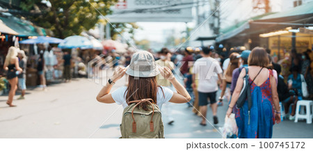 woman traveler visiting in Bangkok, Tourist with backpack and hat sightseeing in Chatuchak Weekend Market, landmark and popular attractions in Bangkok, Thailand. Travel in Southeast Asia concept 100745172