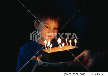 little cute caucasian boy making a wish before puffing out a candle on cake on his 9 birthday 100745175