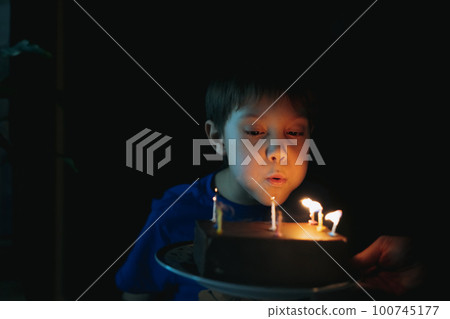 little cute caucasian boy making a wish puffing out candles on cake on his 9 birthday. High quality photo little cute caucasian boy making a wish puffing out candles on cake on his 9 birthday. High quality photo 100745177