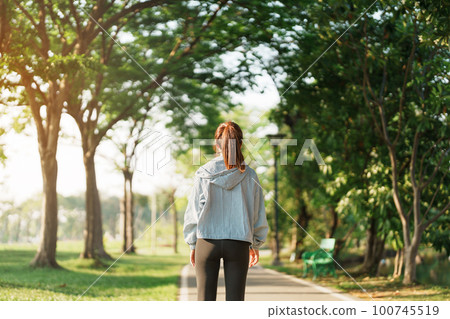 Young adult female in pink sportswear stretching muscle in the park outdoor, sport woman warm up ready for running and jogging in morning. wellness, fitness, exercise and work life balance concepts 100745519