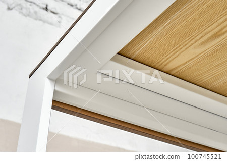 Minimalism style dining table with thin wooden table top of oak veneer on white metal legs in workshop closeup low angle view 100745521
