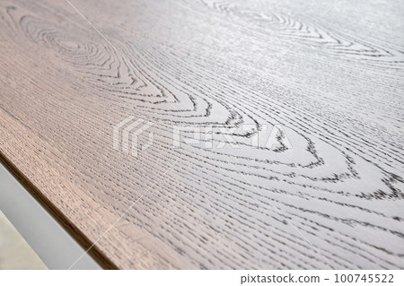 Minimalism style dining table with thin wooden table top of toned oak veneer on white metal legs extreme closeup 100745522