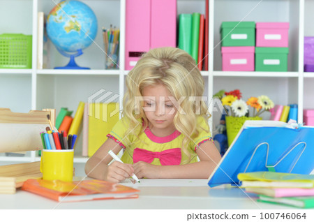 little girl studying at home at the table 100746064
