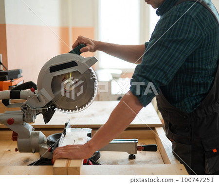 Master cuts the board with a circular saw in the workshop. Master cuts the board with a circular saw in the workshop. 100747251