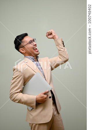 Cheerful and excited Asian businessman celebrating his success, showing clenched fist 100748402