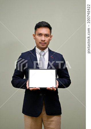 Thoughtful Asian businessman holding a tablet, showing tablet blank screen mockup to camera Thoughtful Asian businessman holding a tablet, showing tablet blank screen mockup to camera 100748422