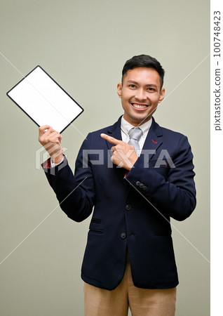 Asian businessman pointing his finger at a tablet while standing against an isolated background 100748423