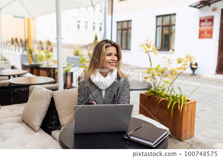 young european woman model in street cafe with laptop in spring 100748575