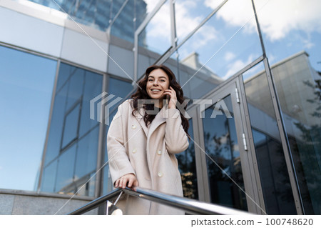 photo of a young woman blogger talking on the phone on the street photo of a young woman blogger talking on the phone on the street 100748620