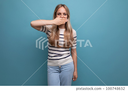 cute girl in casual clothes covered her mouth with her hand on a blue isolated background cute girl in casual clothes covered her mouth with her hand on a blue isolated background 100748632