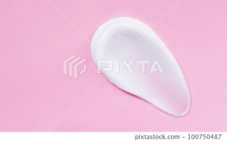 Face cream smear on pink background. White lotion swatch. Abstract cosmetic cream texture. 100750487