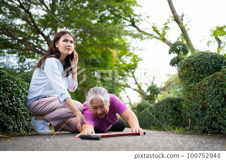 Asian senior woman fell down on lying floor because faint and limb weakness and pain from accident and woman came to help support and call emergency. Concept of old elderly insurance and health care Asian senior woman fell down on lying floor because faint and limb weakness and pain from accident and woman came to help support and call emergency. Concept of old elderly insurance and health care 100752948
