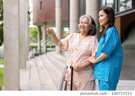 Asian careful caregiver or nurse hold patient hand and encourage patient, walking in garden. Concept of happy retirement with care from a caregiver and Savings and senior health insurance. Asian careful caregiver or nurse hold patient hand and encourage patient, walking in garden. Concept of happy retirement with care from a caregiver and Savings and senior health insurance. 100753553
