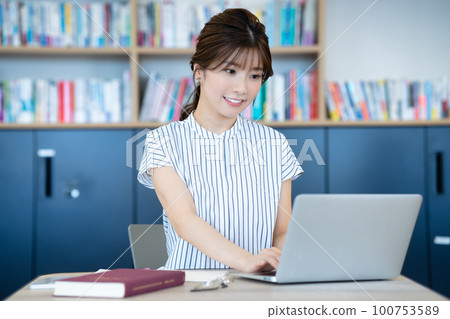 Young woman using a laptop in the library 100753589
