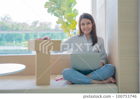 Happy young Asian woman entrepreneur, Hold package and Smile for sale success of online shopping store at home office, Concept of merchant, small business, online business and eCommerce. Happy young Asian woman entrepreneur, Hold package and Smile for sale success of online shopping store at home office, Concept of merchant, small business, online business and eCommerce. 100753746