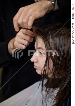 male hairdresser is combing the hair of the female client. male hairdresser is combing the hair of the female client. 100754611
